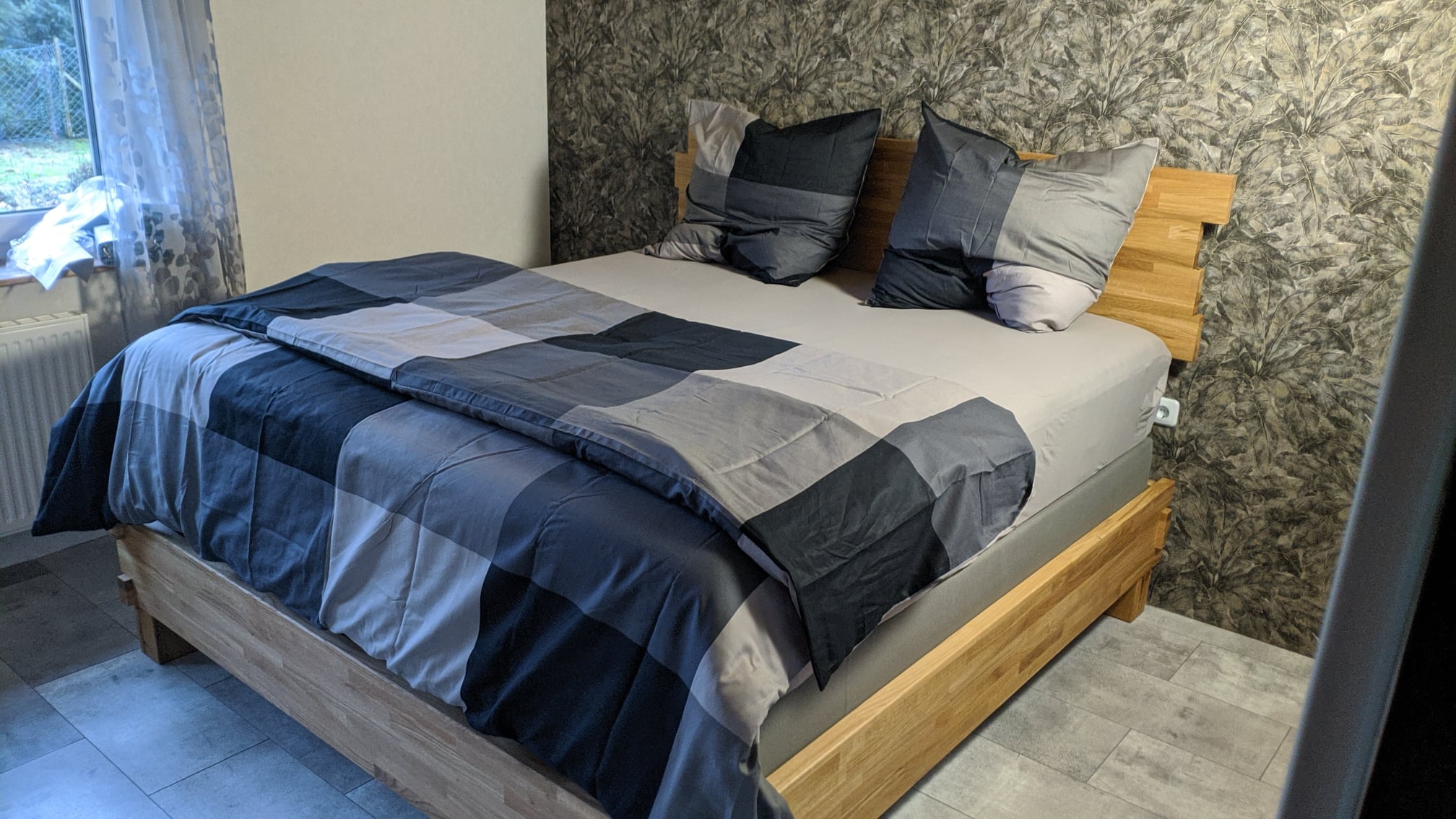 Fertiges Massivholzbett mit geölter Oberfläche im Schlafzimmer