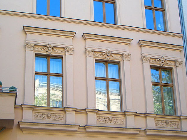 Neue Holzfenster in einer sanierten Altbaufassade mit Stuckelementen