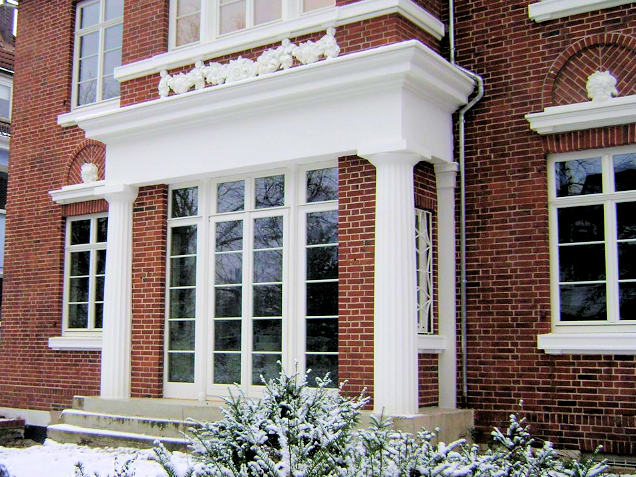 Weiße Holzfenster in einem Erker an einem Altbau mit Backsteinfassade