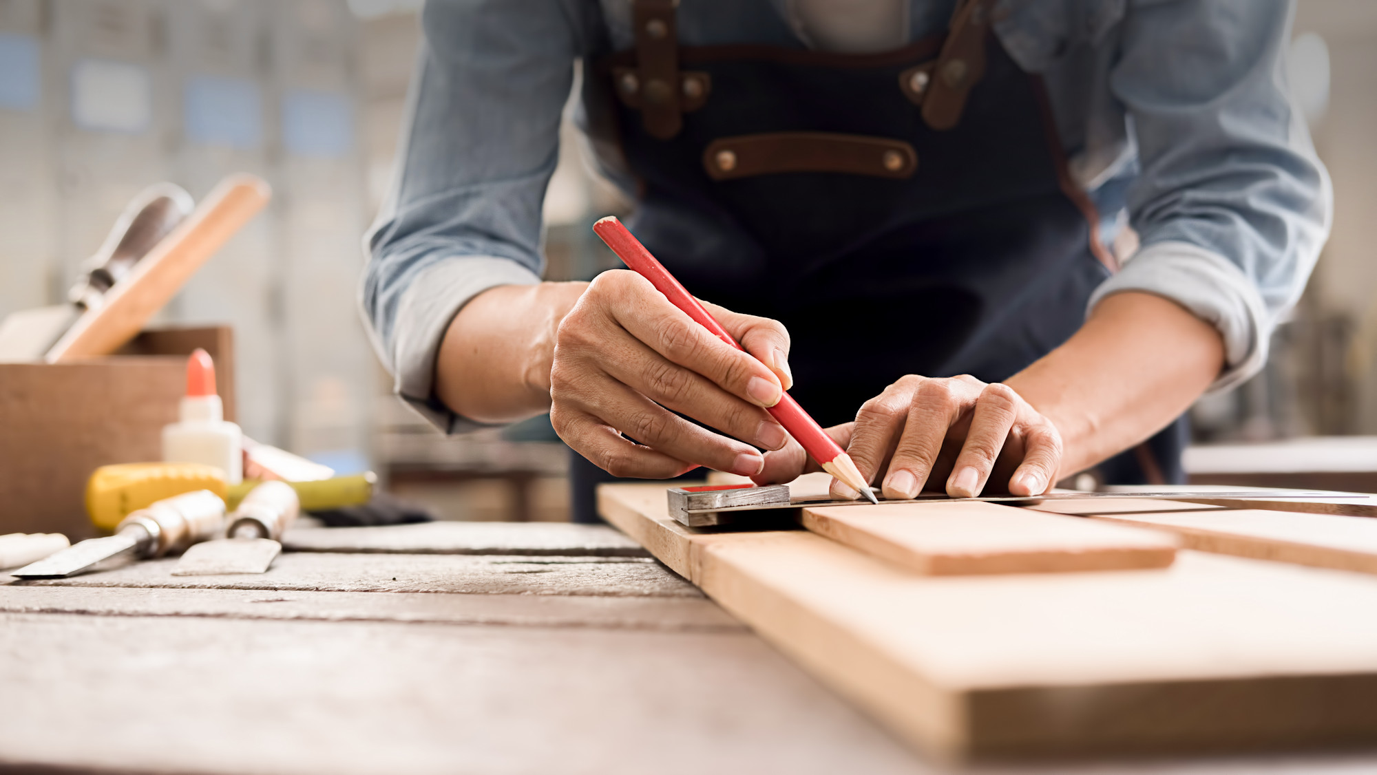 Tischler zeichnet mit Bleistift und Winkel auf einem Holzbrett an