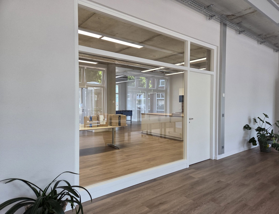 Lichtdurchflutete Glastrennwand mit Blockrahmenelementen aus Whitewood