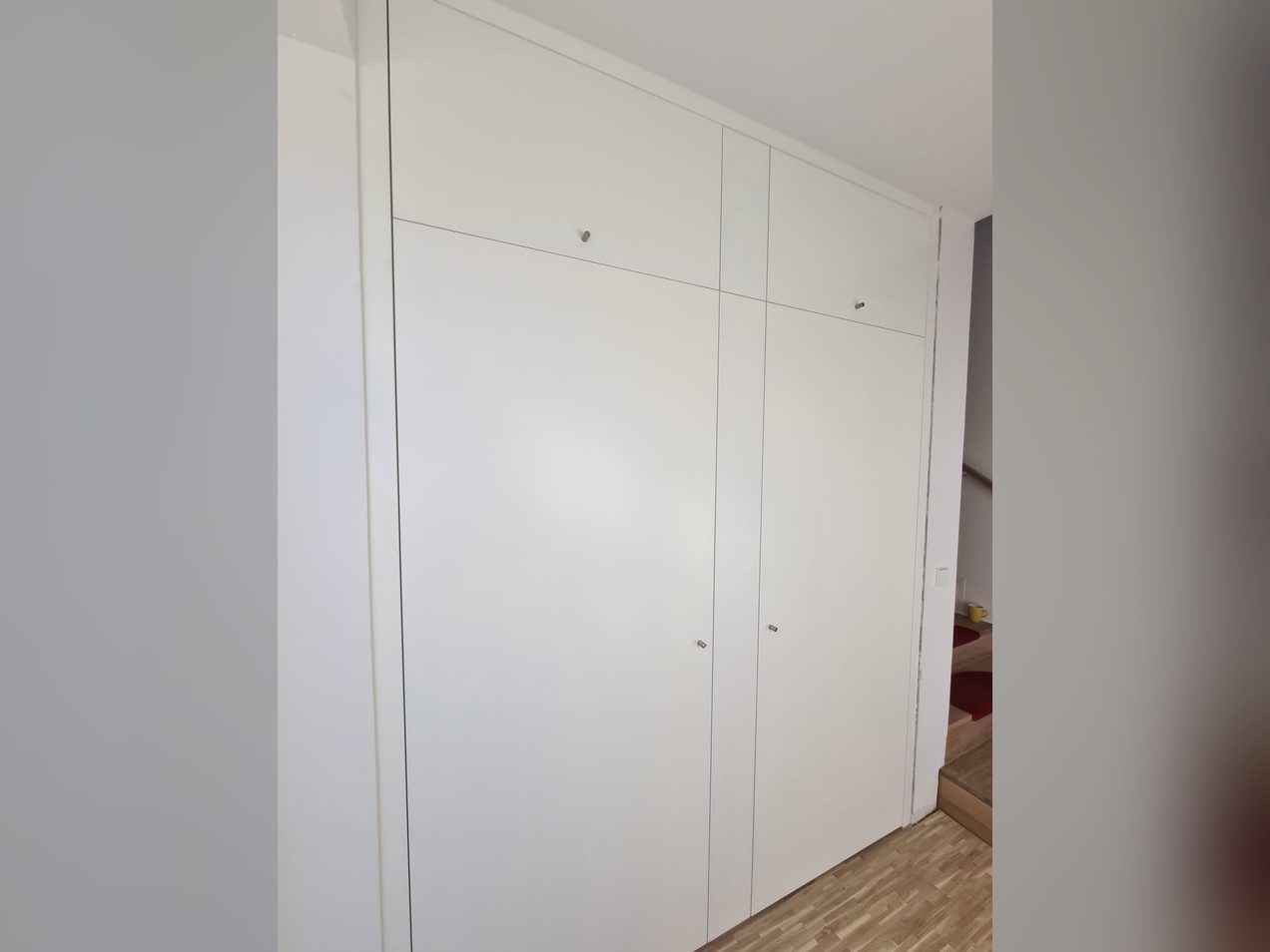 Raumhoher weißer Einbauschrank mit grifflosen Fronten, nach Maß gefertigt