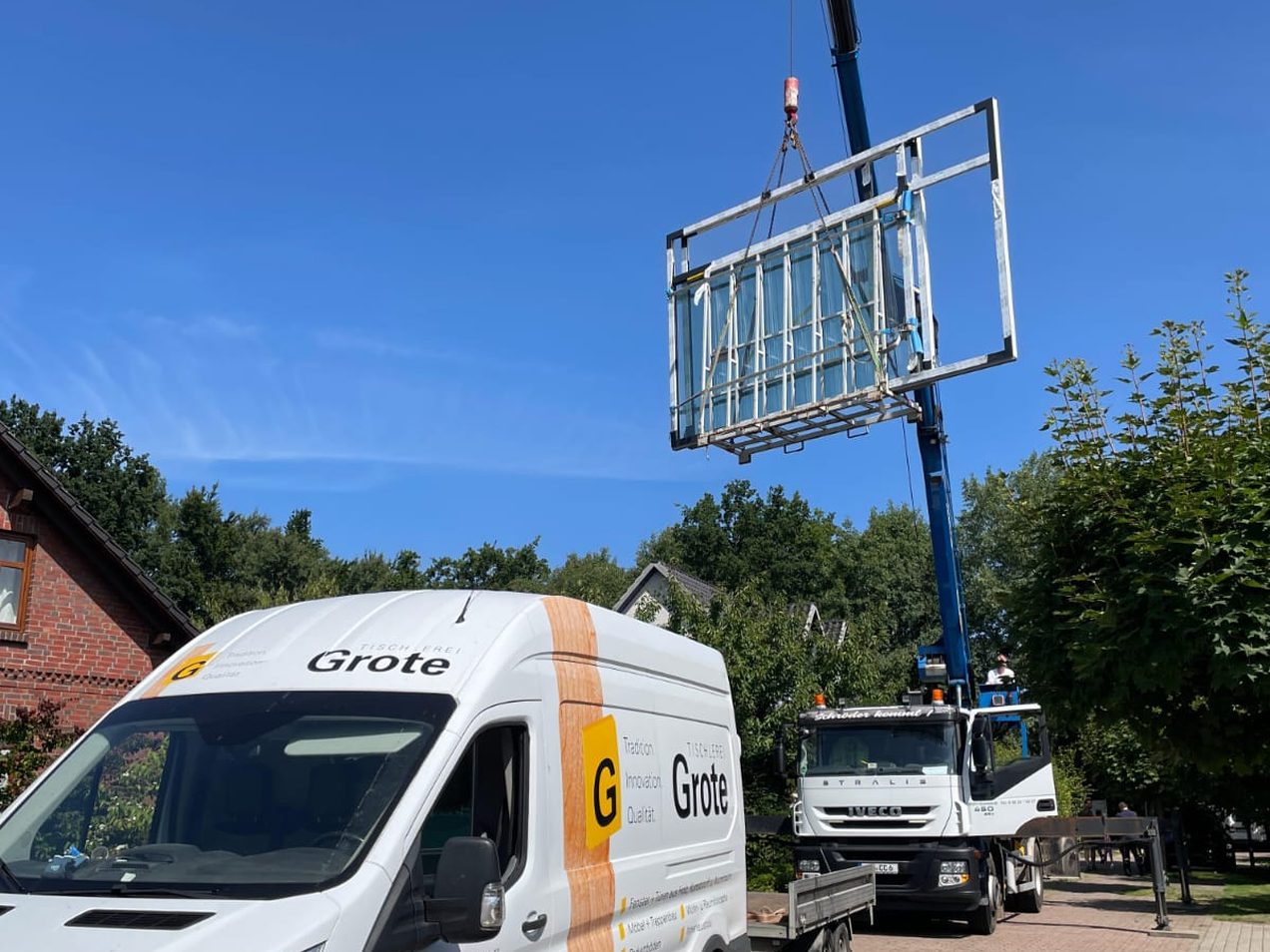 Fenstermontage: Ein Kran hebt ein großes Fensterelement, davor der Transporter der Tischlerei Grote