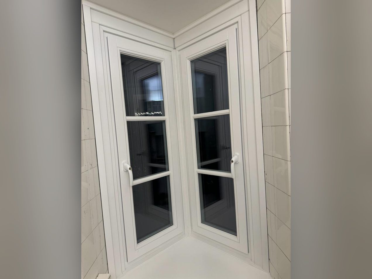 Weiße zweiflügelige Holzfenster mit Sprossen in einer Fensternische
