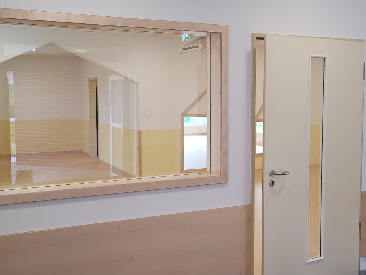 Innenfenster mit hellem Holzrahmen und Zimmertür mit schmalem Glasausschnitt