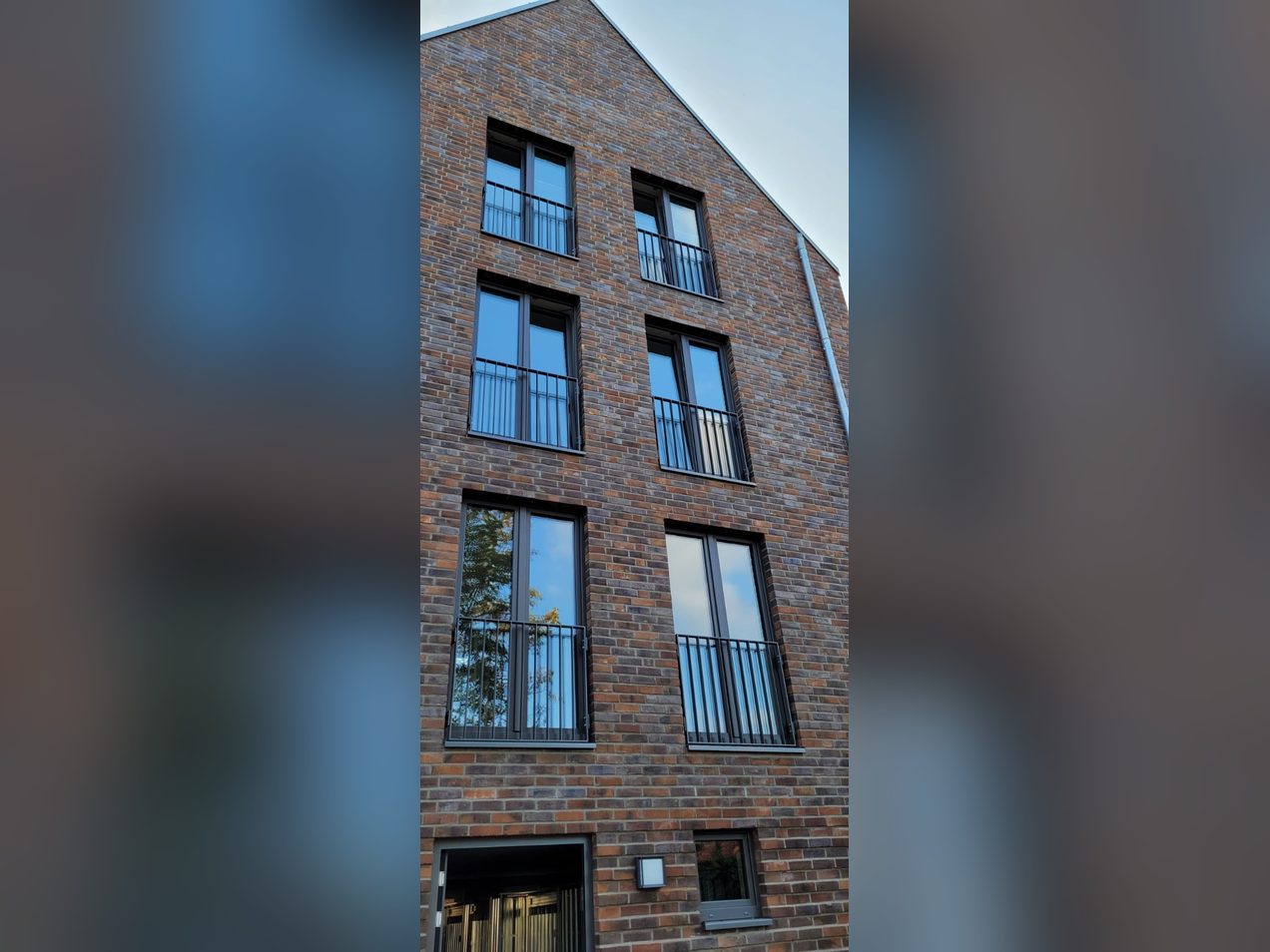 Anthrazitfarbene Kunststofffenster mit französischen Balkonen an einem Mehrfamilienhaus mit Klinkerfassade