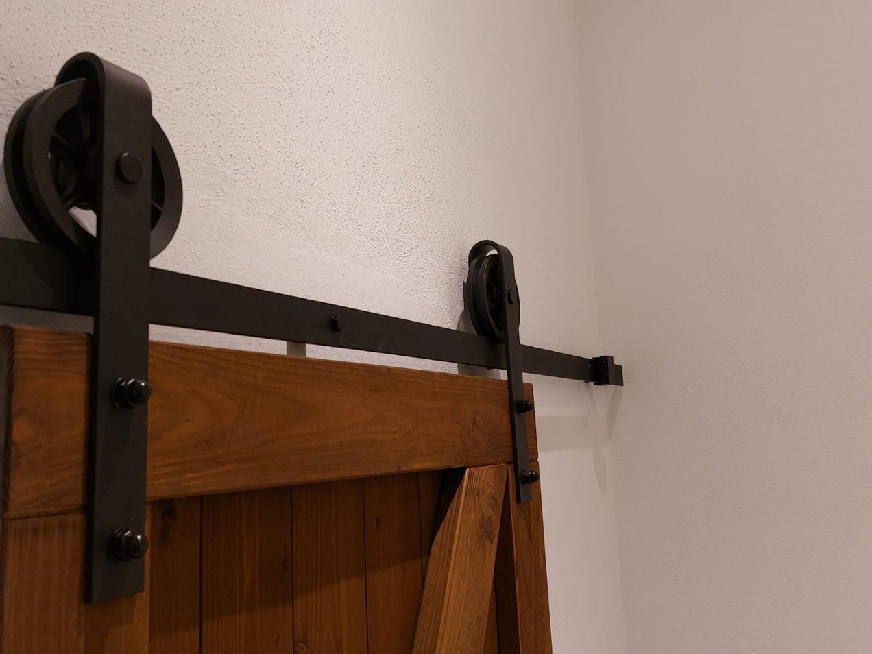 Detail der schwarzen Laufschiene mit Rollen einer Holz-Schiebetür