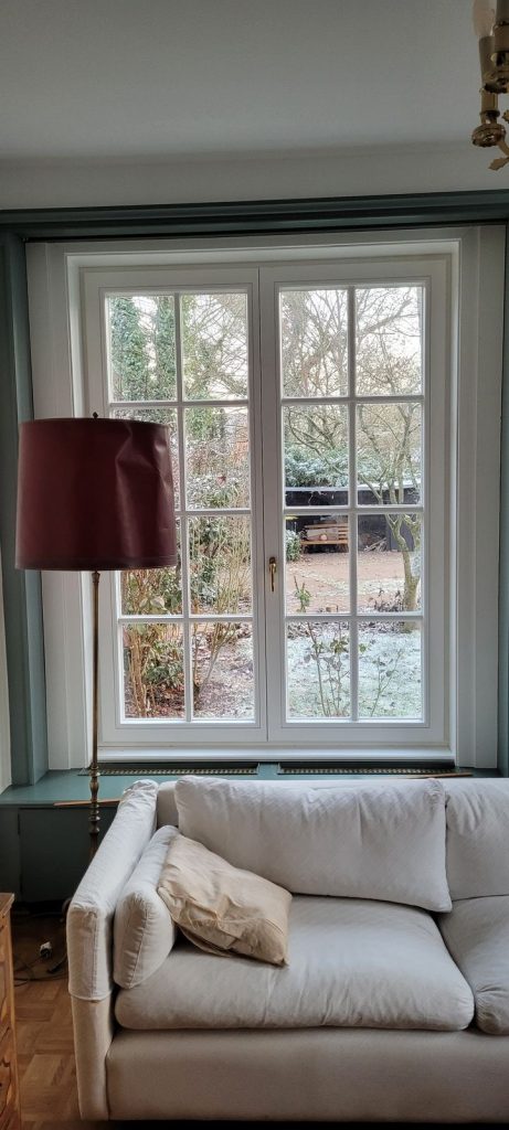 Klassisches weißes Sprossenfenster im Wohnzimmer mit Blick in den Garten